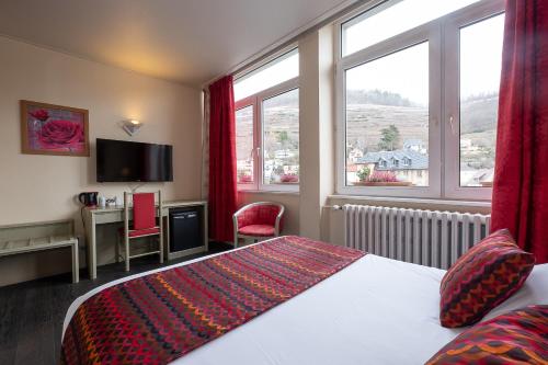 a hotel room with a bed and a large window at The Originals City Hotel de l Ange Guebwiller in Guebwiller