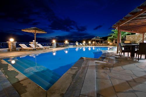 a swimming pool at night with chairs and an umbrella at Hermes-Ios Rooms To Let in Ios Chora