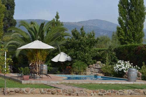a pool with an umbrella and a table and chairs at Hotel Posada Colchagua in Santa Cruz