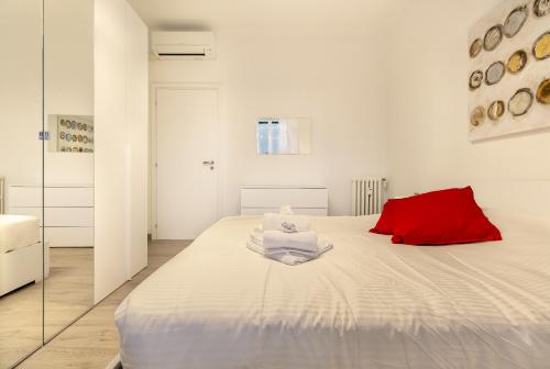 Schlafzimmer mit einem großen weißen Bett und einem roten Kissen in der Unterkunft YouHosty - Pantigliate 8 in Mailand