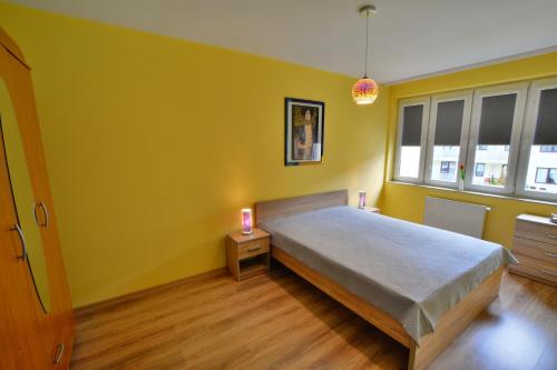 a bedroom with a bed and a yellow wall at ApartamentyPrzyMorzu Zielone Tarasy in Kołobrzeg