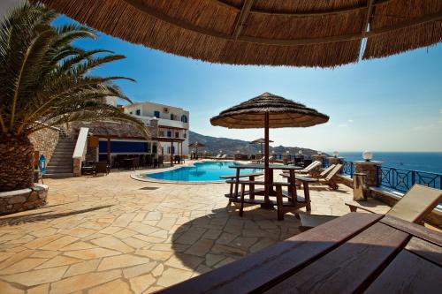 a resort with a swimming pool and an umbrella at Hermes-Ios Rooms To Let in Ios Chora
