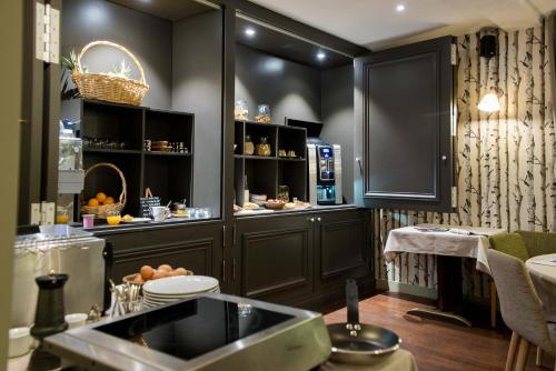 una cocina con armarios negros y fregadero. en Logis Hôtel Tante Yvonne & son restaurant semi-gastronomique - Lyon Nord en Quincieux