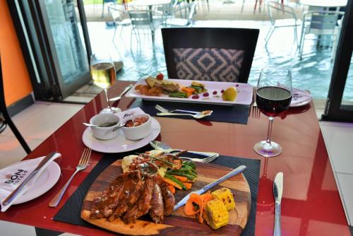 a table with a plate of food and glasses of wine at BON Hotel Waterfront Richards Bay in Richards Bay