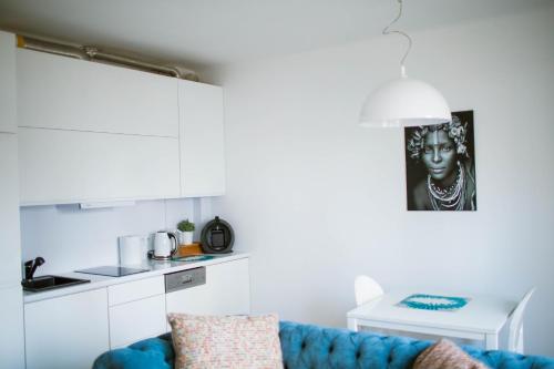 a living room with a blue couch and a kitchen at Flat White Apartament Pułtusk in Pułtusk