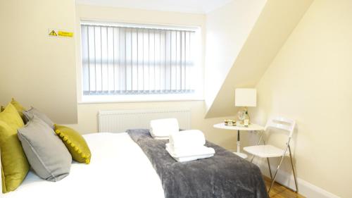 a bedroom with a bed and a window and a table at RC Airport Rooms in Stanwell