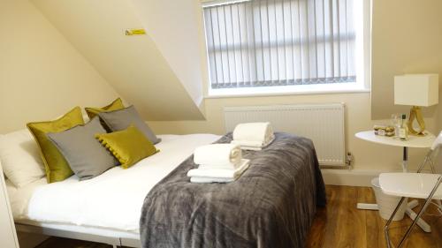 a bedroom with a bed with towels on it at RC Airport Rooms in Stanwell