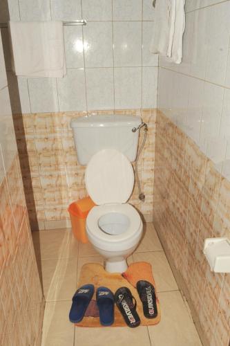 a bathroom with a toilet and a pair of shoes at Scroll Inn Hotel in Kampala