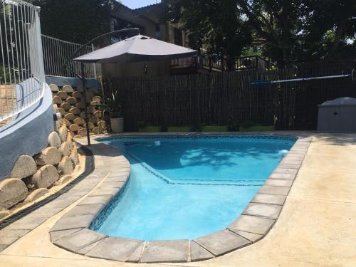 a swimming pool with an umbrella next to a fence at Sabie Self Catering Apartments in Sabie