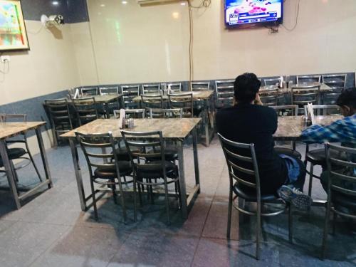 a group of people sitting at tables in a restaurant at Asha Guest House in Amritsar