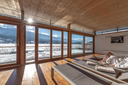 a person laying on a bed in a room with windows at Lake Resort Pressegger See in Hermagor