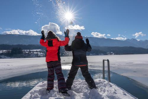 two people standing in the snow with their hands in the air at Lake Resort Pressegger See in Hermagor