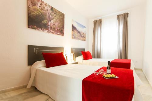 a hotel room with two beds and a red table at Apartamentos El Tajo & SPA in Ronda