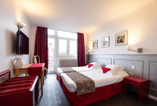 a hotel room with two beds and a window at The Originals City Hotel de l Ange Guebwiller in Guebwiller