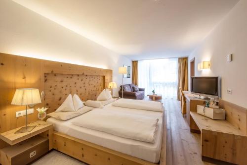 Habitación de hotel con cama grande y TV en Alpine Hotel Ciasa Lara, en La Villa