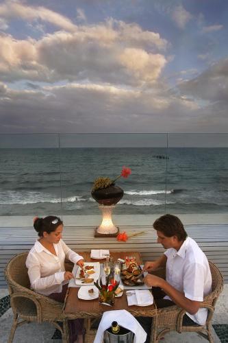 a man and woman sitting at a table on the beach at The Promenade in Puducherry