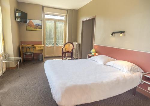 a hotel room with a large bed and a desk at Hotel Au Val Doré in La Bourboule
