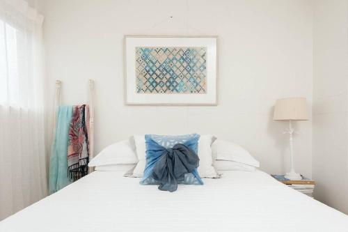 Una cama blanca con una almohada azul. en Home with a View with Pool and Roof Terrace Garden en Sídney