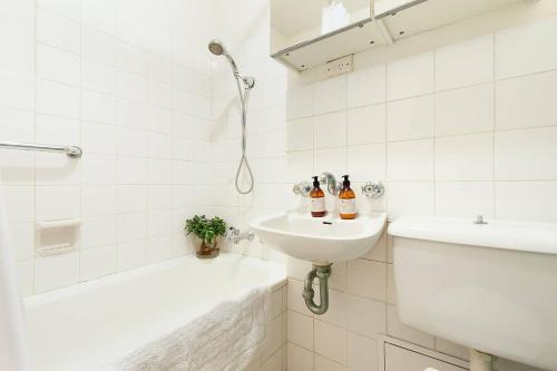 uma casa de banho branca com um lavatório, uma banheira e um WC. em Home with a View with Pool and Roof Terrace Garden em Sidney