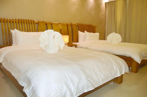 una camera con due letti con lenzuola bianche di Yara Suites a Buraydah