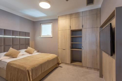 a bedroom with a bed and a flat screen tv at Hotel Aurora Family & SPA in Międzyzdroje