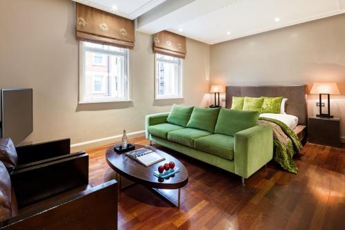 a living room with a green couch and a bed at Radisson Blu Hotel, London Tottenham Court Road in London