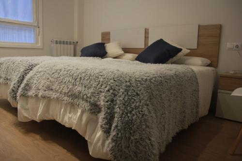 um quarto com uma cama grande e um cobertor cinzento em Apartamento Erdi Kale em Azpeitia