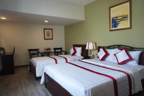 a hotel room with two beds and a table with chairs at Hue My Hotel in Ho Chi Minh City