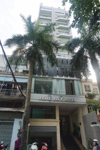 a hotel with a palm tree in front of a building at Hue My Hotel in Ho Chi Minh City