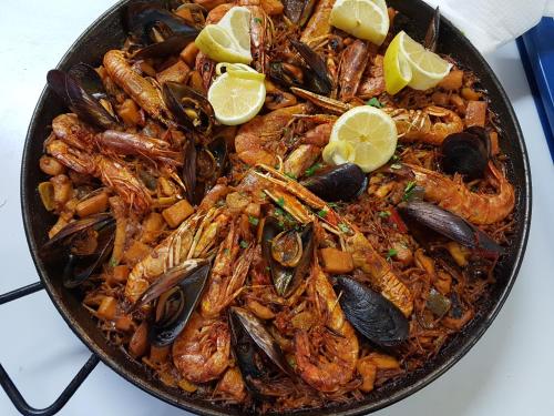 a pan of food with shrimp and mussels and lemon slices at Hotel La Cala in Roses