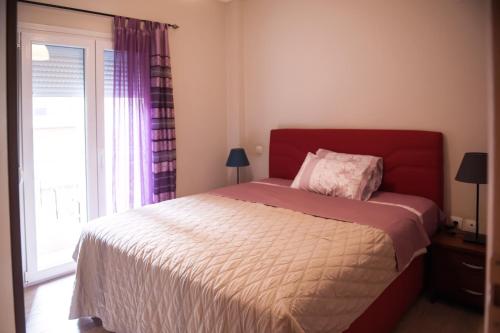 sypialnia z łóżkiem z czerwonym zagłówkiem i oknem w obiekcie City House Apartment w Salonikach