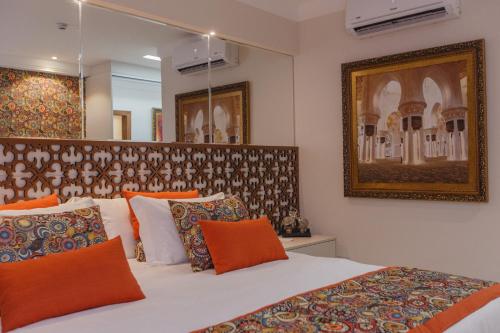 a bedroom with a large bed with orange pillows at Golden Lis Hotel Boutique in Goiânia