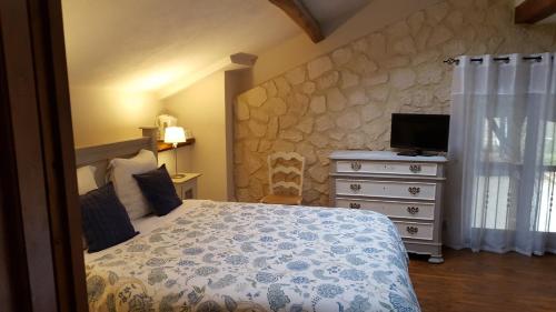 a bedroom with a bed and a dresser with a television at Les Tilleuls in Saint-Pé-Delbosc