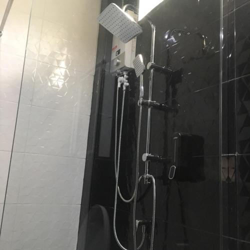 a shower in a bathroom with a black tile wall at The Loft Resort Kabin Buri in Kabin Buri