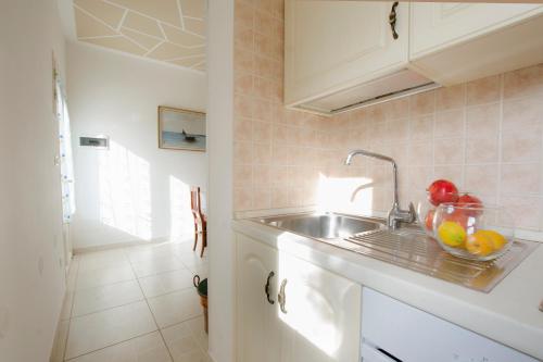 een keuken met een spoelbak en een schaal fruit bij Le Gioie - Dimora Scalelle - Villetta con giardino e veranda vista mare in Torre Vado