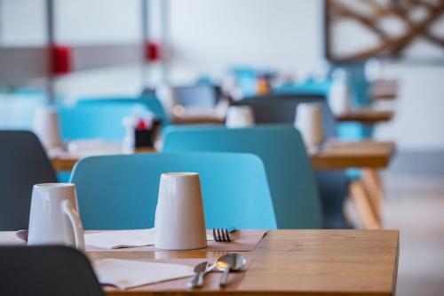a wooden table with two napkins and blue chairs at Mercure Paris Vaugirard Porte De Versailles in Paris