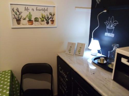 einen Schreibtisch mit einer Lampe und ein Bild von Pflanzen an der Wand in der Unterkunft Comfy Studio in Lamía