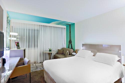 a bedroom with a large white bed and a chair at Mercure Paris Vaugirard Porte De Versailles in Paris