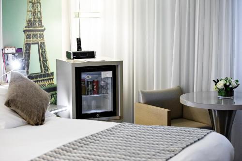 a hotel room with a bed and a table and the eiffel tower at Mercure Paris Vaugirard Porte De Versailles in Paris