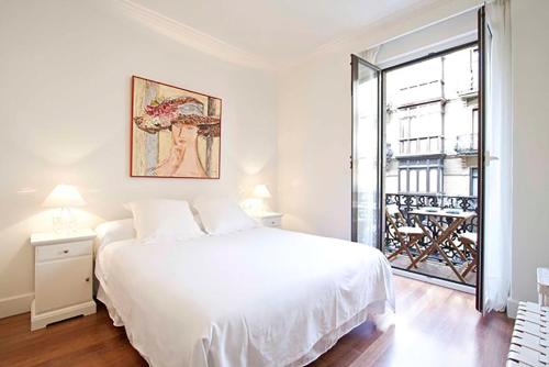 ein weißes Schlafzimmer mit einem großen weißen Bett und einem Fenster in der Unterkunft The Rentals Collection | Leonardo in San Sebastián