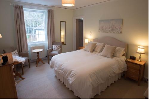 a bedroom with a large white bed and a chair at Elibank House Apartment in Walkerburn
