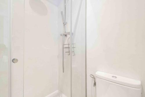 uma casa de banho branca com um chuveiro e um WC. em The Rentals Collection | Gros Beach em San Sebastián