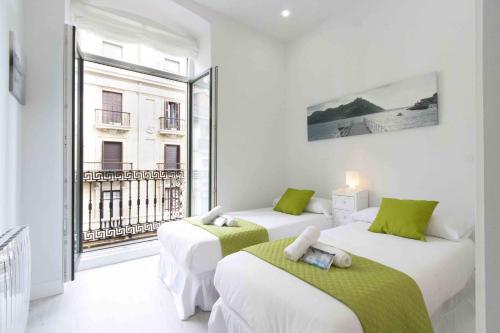 two beds in a room with a large window at The Rentals Collection | Okendo I in San Sebastián