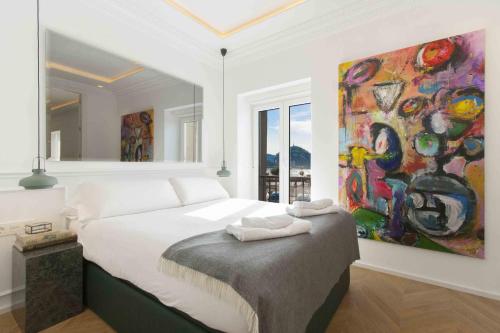 una camera da letto con un letto e un dipinto sul muro di The Rentals Collection | Scala a San Sebastián