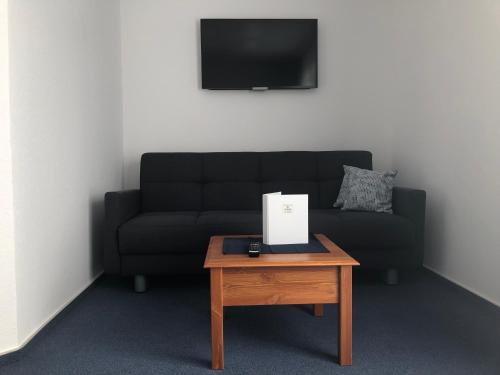 a living room with a black couch and a table at Gasthof Zur Krone in Leidersbach