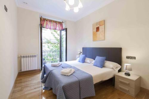 sypialnia z dużym łóżkiem z niebieskimi poduszkami w obiekcie The Rentals Collection | Camelot w mieście San Sebastián