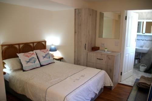 a bedroom with a bed with two pillows and a sink at Fisherman's Watch Cottage in Cape Town