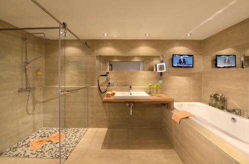 a bathroom with a shower and a sink and a tub at Parkhotel Oberhausen in Oberhausen