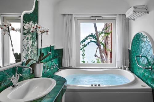 a bath tub sitting next to a window in a bathroom at Hotel Santa Caterina in Amalfi
