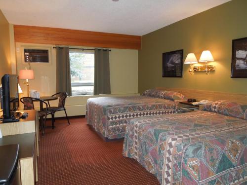 Habitación de hotel con 2 camas y escritorio en Walking Eagle Inn & Lodge en Rocky Mountain House